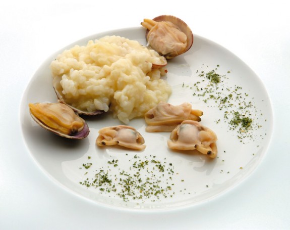 Plato de arroz cremoso con almejas y perejil en un plato blanco